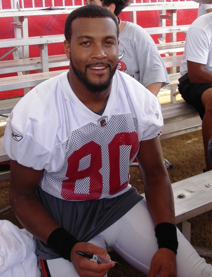 An exhausted wide receiver Michael Clayton sits in the bleachers with fans after practice Sunday.