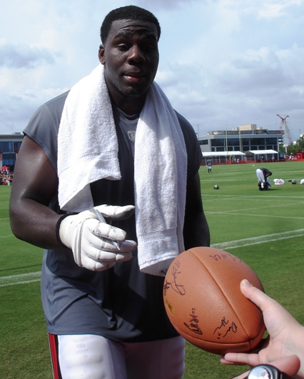 Offensive lineman Demar Dotson autographs a football for a fan.