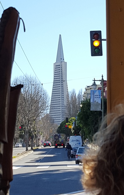 Looking down a street while cruising through the city on a cable car.