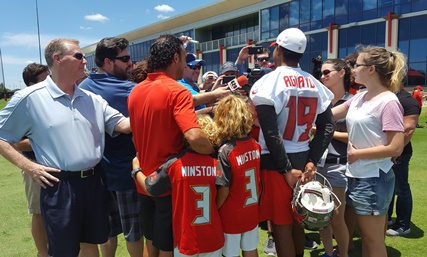 Former Bucs kicker Martin Gramatica (red shirt) with his two sons as well as current Bucs kicker Roberto Aguayo (19) surrounded by a gaggle of reporters after Bucs OTA practice today.